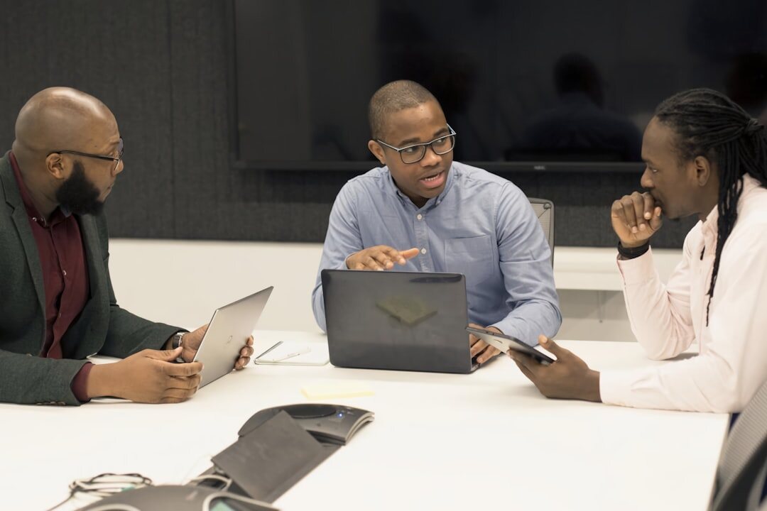 Professionals having a roundtable discussion with laptops and notes